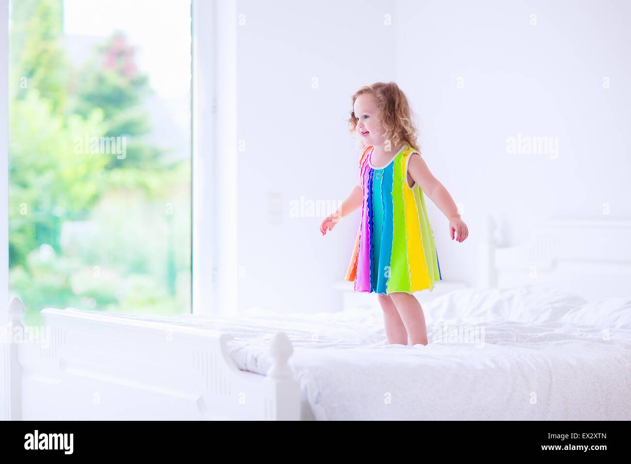 Children jump on a bed. Cute little girl jumping and dancing in a sunny