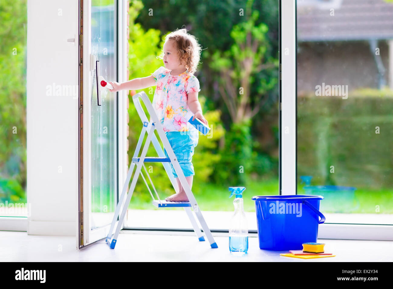 Little girl washing a window. Kids clean the house. Children help at home. Toddler kid cleaning windows and doors Stock Photo