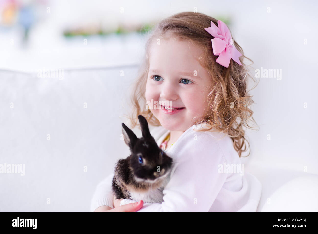 Child playing with a real rabbit. Kids play with pets. Little girl