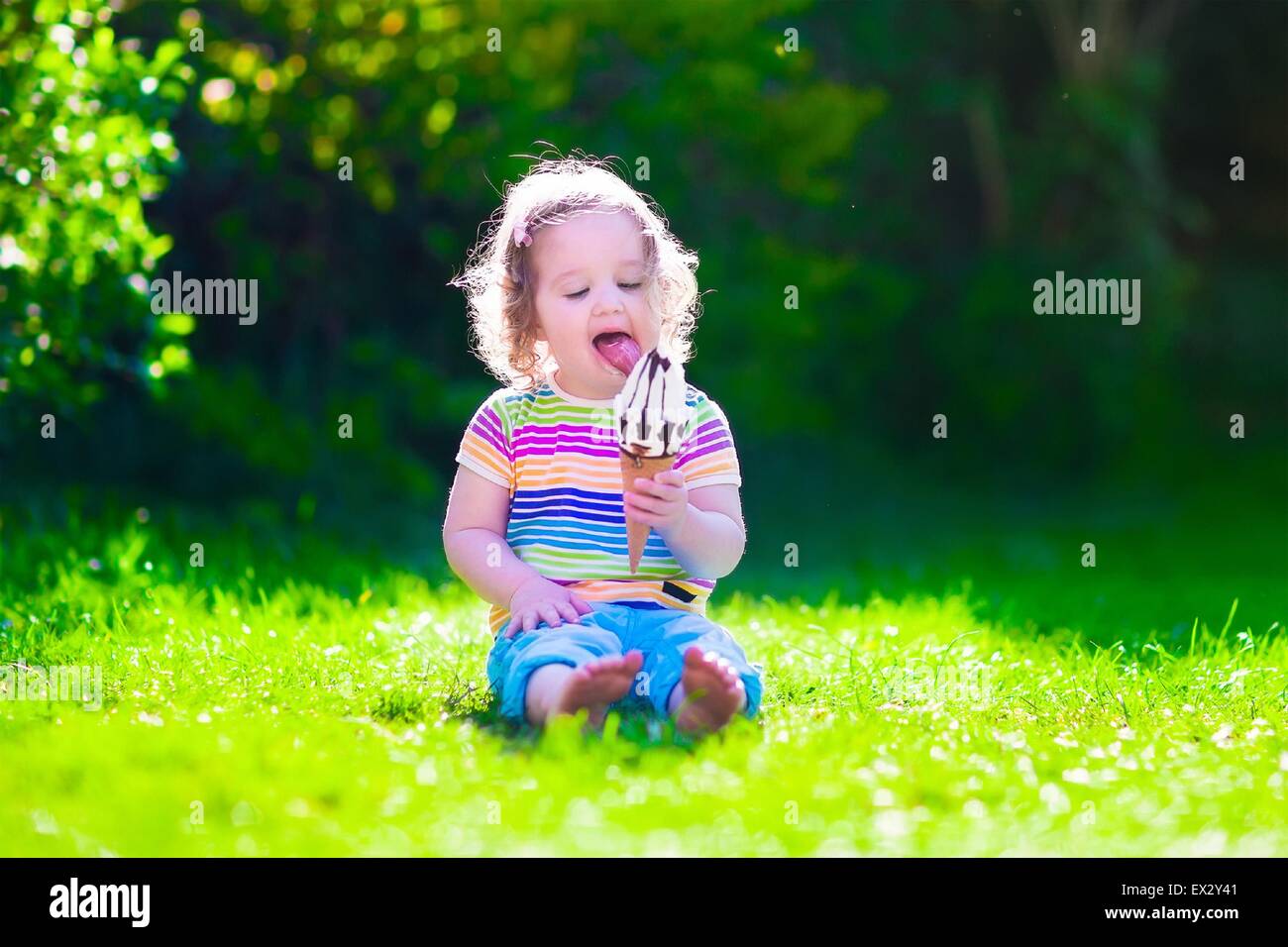 Child eating ice cream. Kids play outdoors enjoying sweet snack on a hot summer day. Children eat icecream. Stock Photo