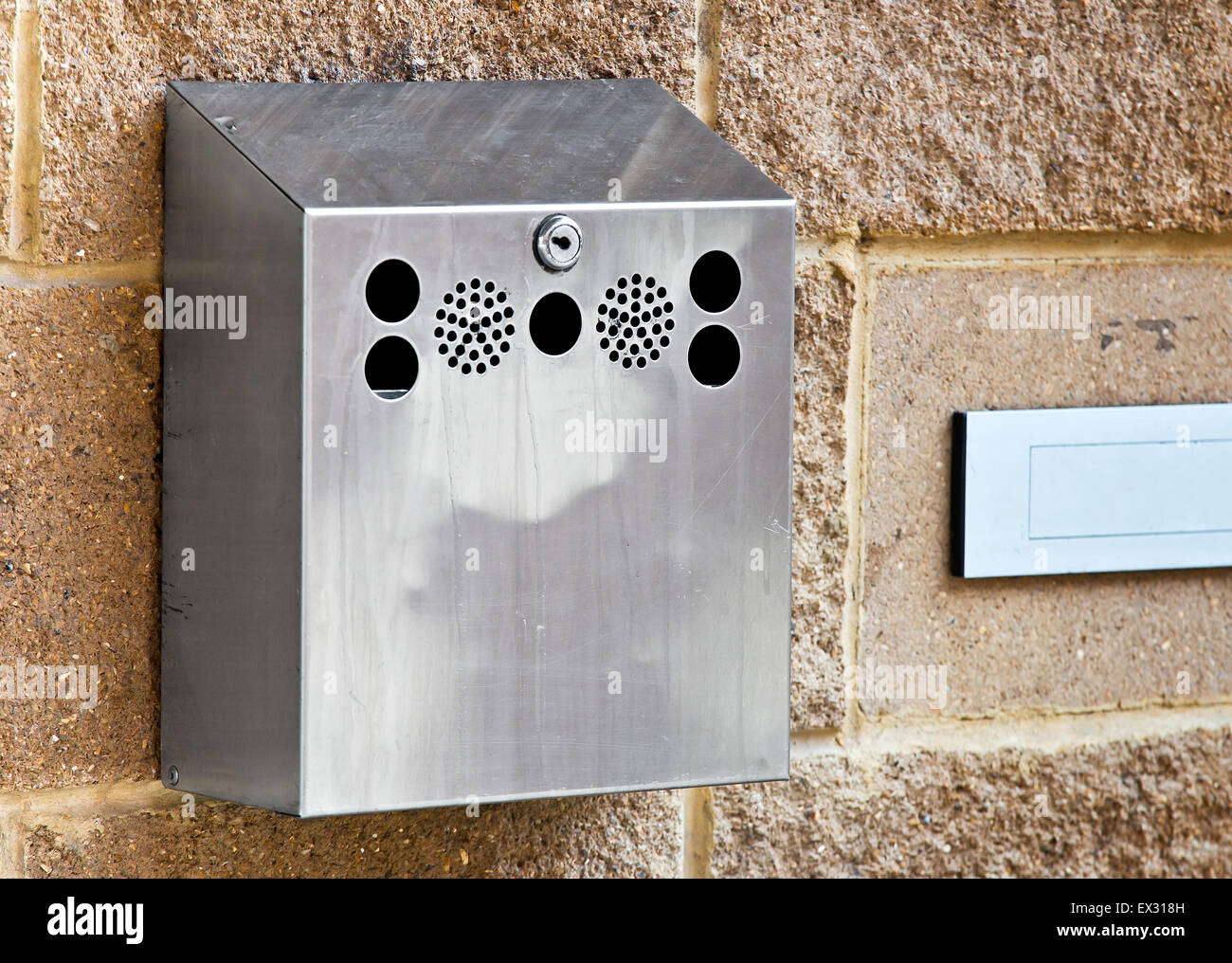 Wallmounted stainless steel cigarette bin on an exterior wall outside a place of work where smoking is banned inside. This enabl Stock Photo