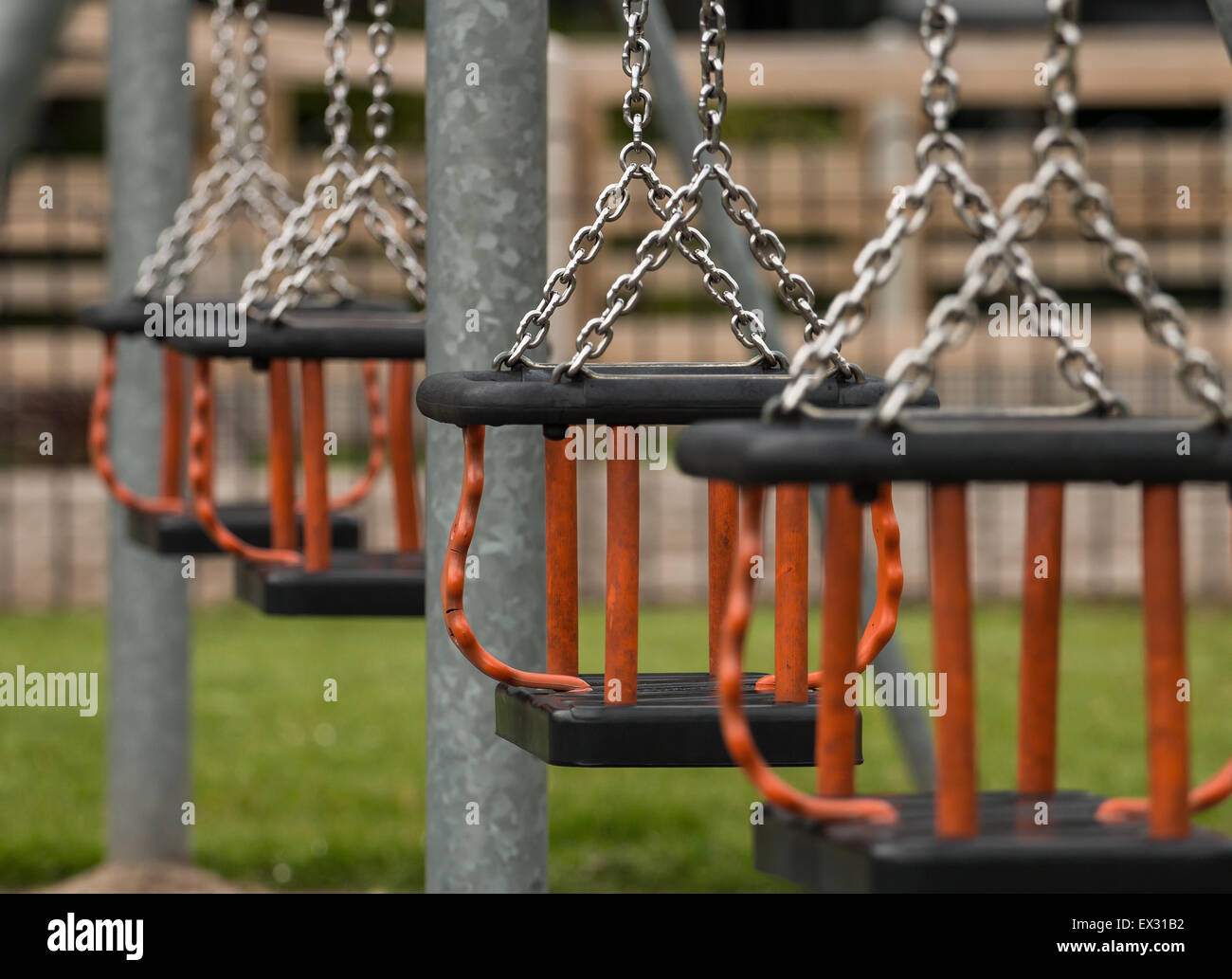 Row of swing seats at a local play park or children's playground provided by the local council for children to have fun in their Stock Photo