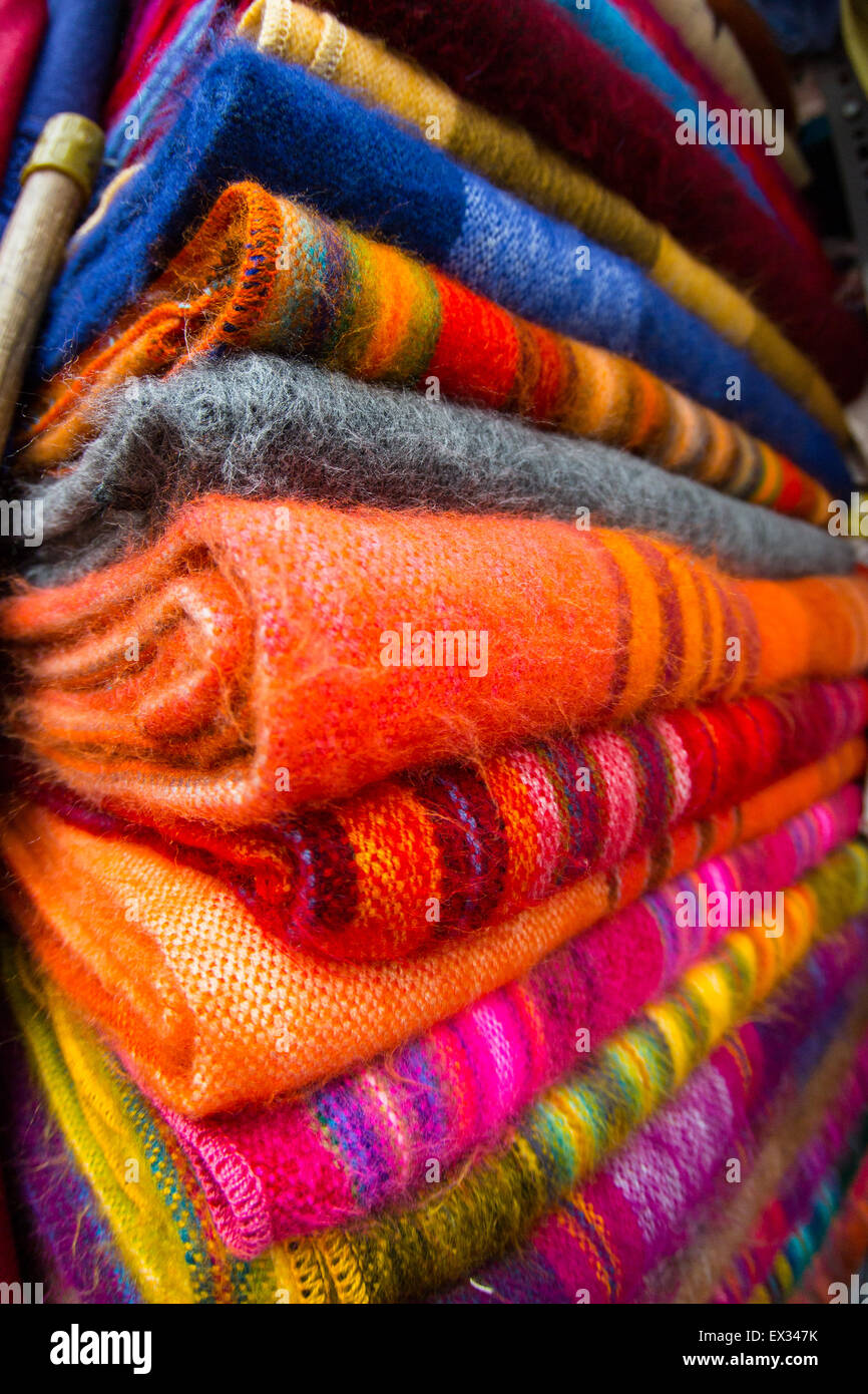 Vibrant tapestries carefully folded and stacked at a market in Quito, Ecuador. Stock Photo
