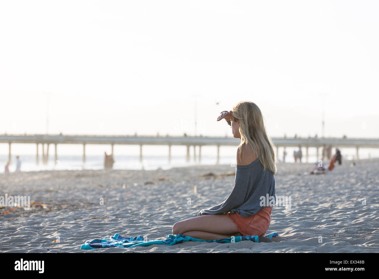 A woman thinks while staring at the ocean during late afternoon. Stock Photo