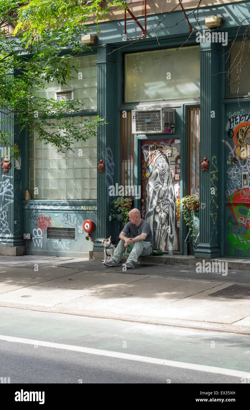 Man and his dog sitting outside on a street in the Lower East Side in New York City Stock Photo