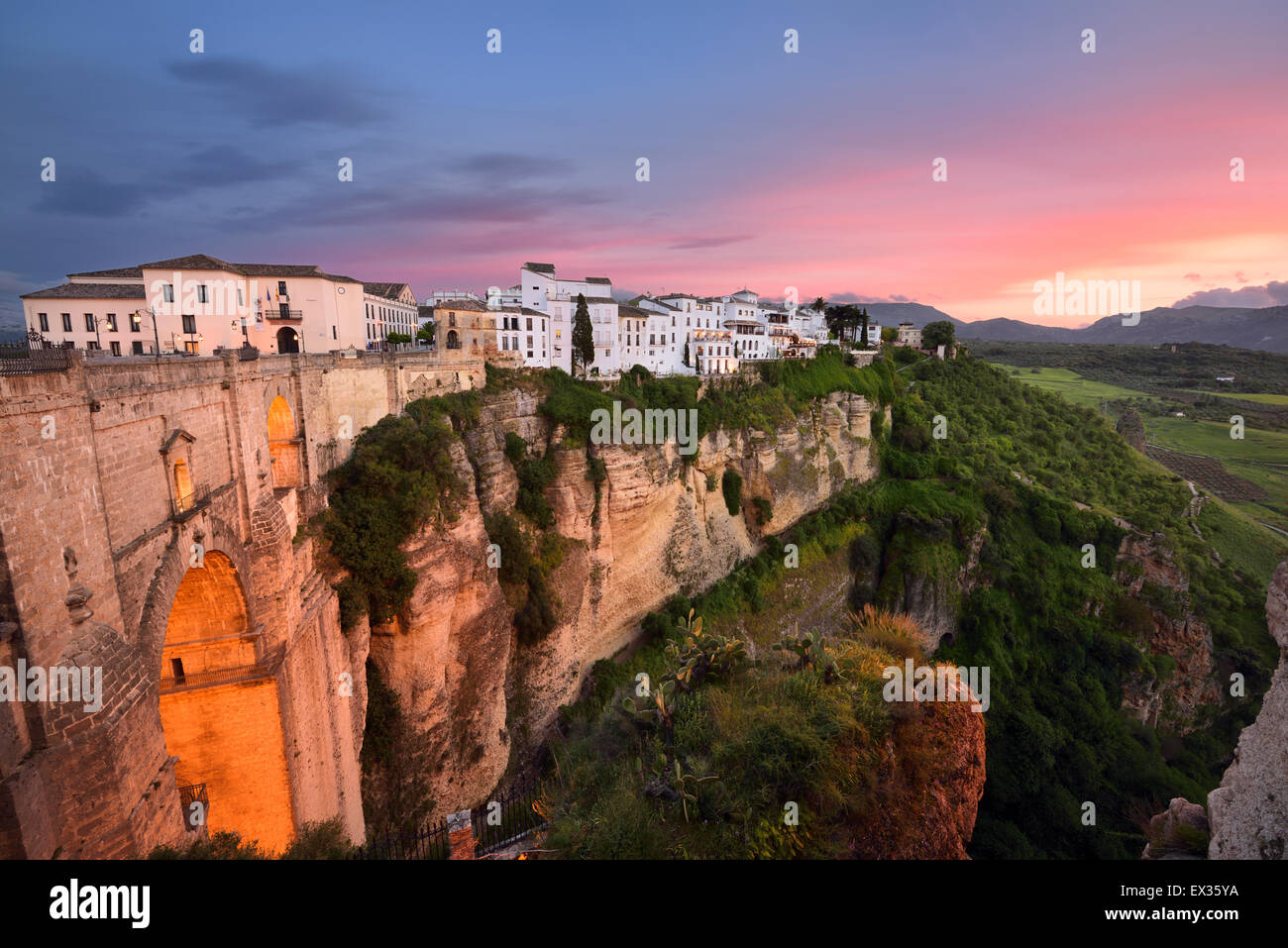 Red sky evening light on white buildings and orange cliffs at El Tajo Gorge Ronda Spain at the Guadalevin river gorge Stock Photo
