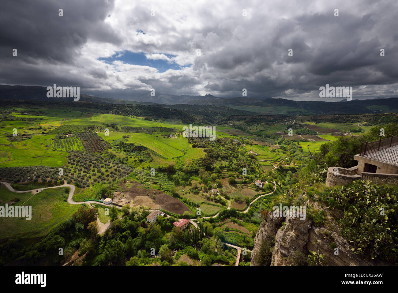 Dappled sunshine on green farm fields in valley below the mountain city of Ronda Spain Stock Photo