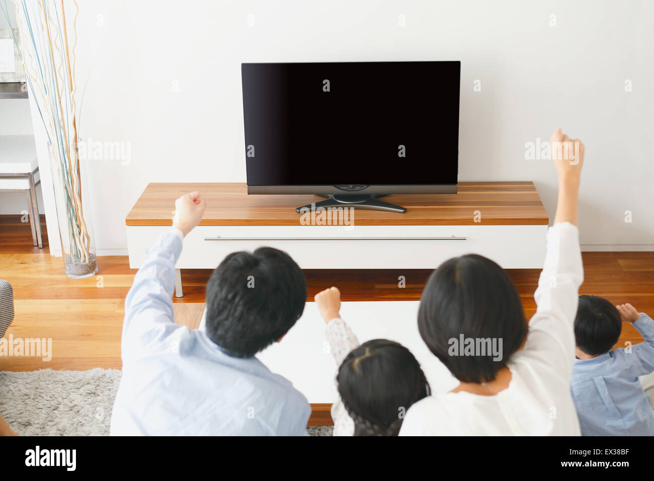 Young Japanese family watching TV in the living room Stock Photo