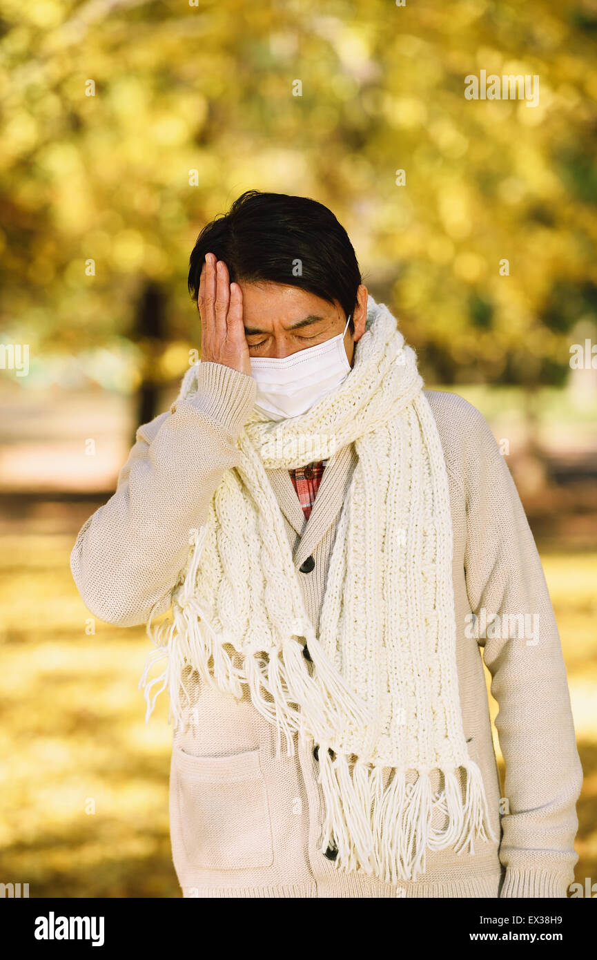 Senior Japanese man with mask feeling sick Stock Photo