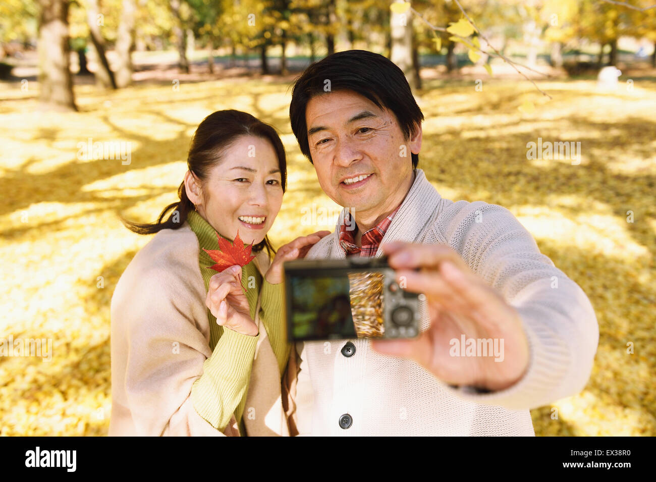 Senior Japanese couple taking pictures in a city park in Autumn Stock ...