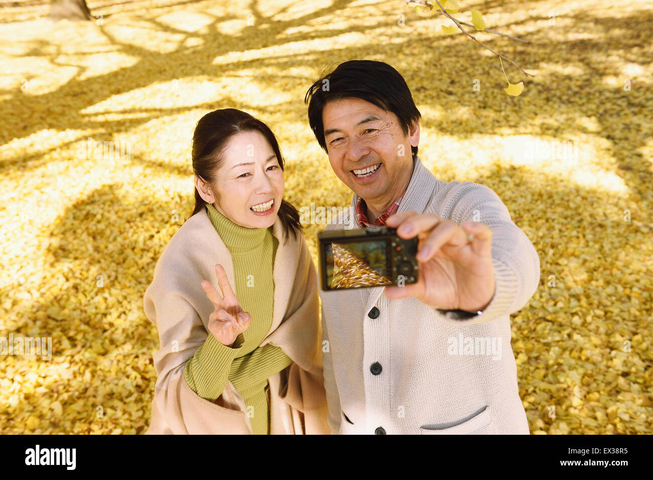 Senior Japanese couple taking pictures in a city park in Autumn Stock ...