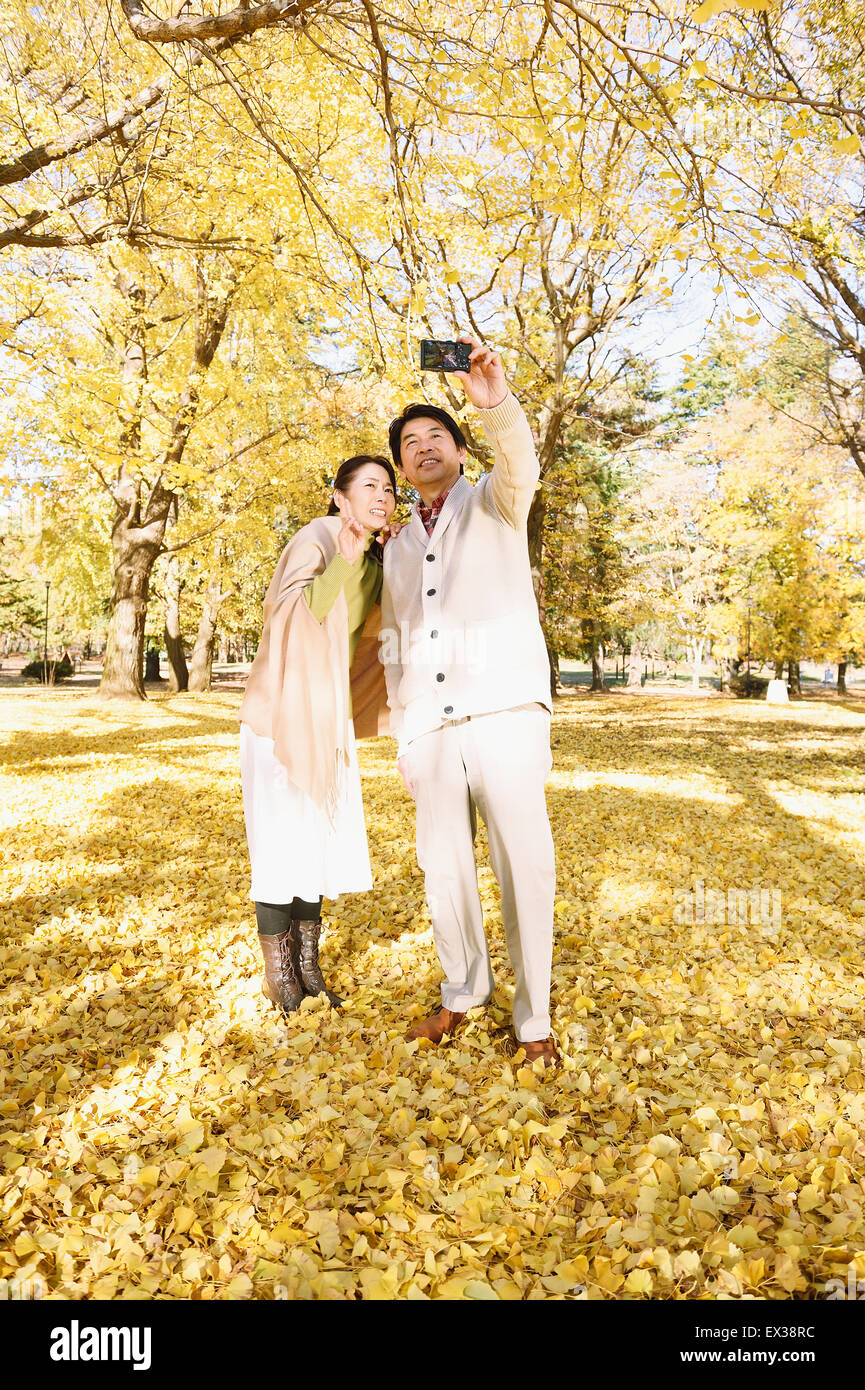 Senior Japanese couple taking pictures in a city park in Autumn Stock ...