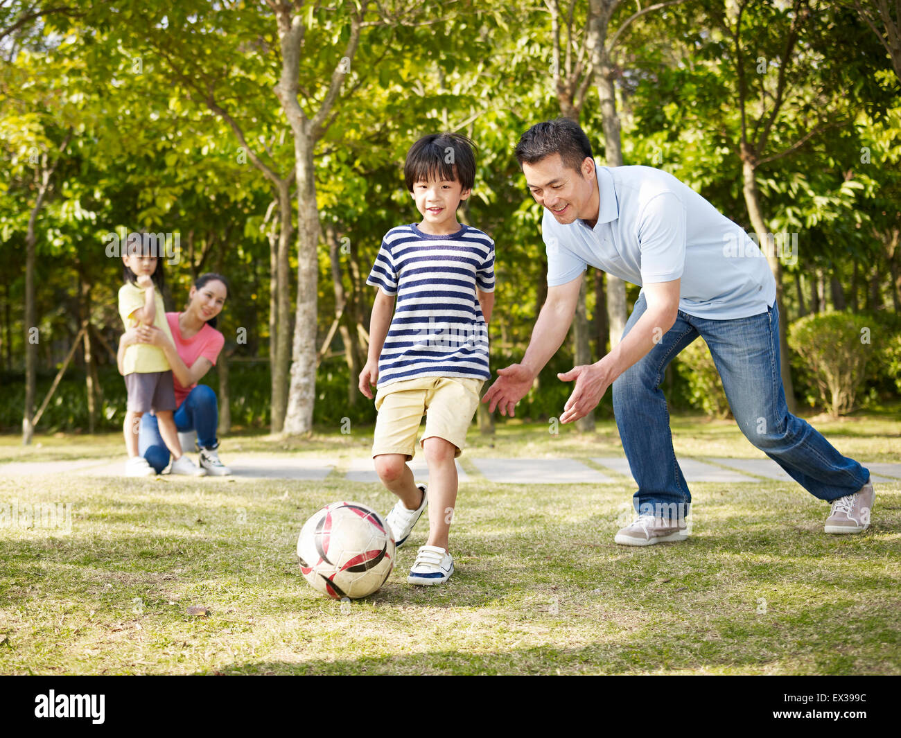 asian father teaching son to play soccer (football) Stock Photo