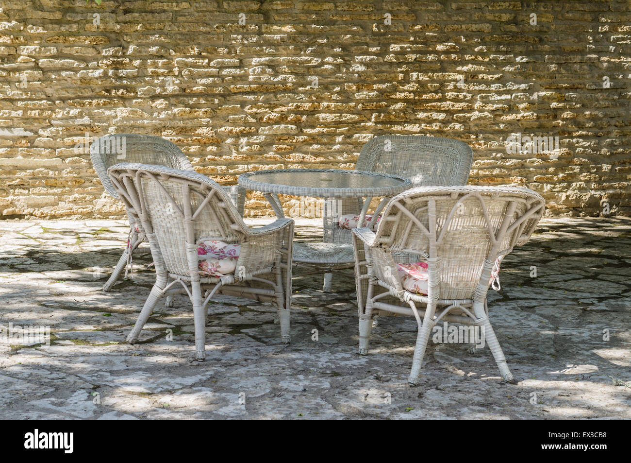 Outdoor terrace at courtyard with limestone wall, cane chair furniture Stock Photo