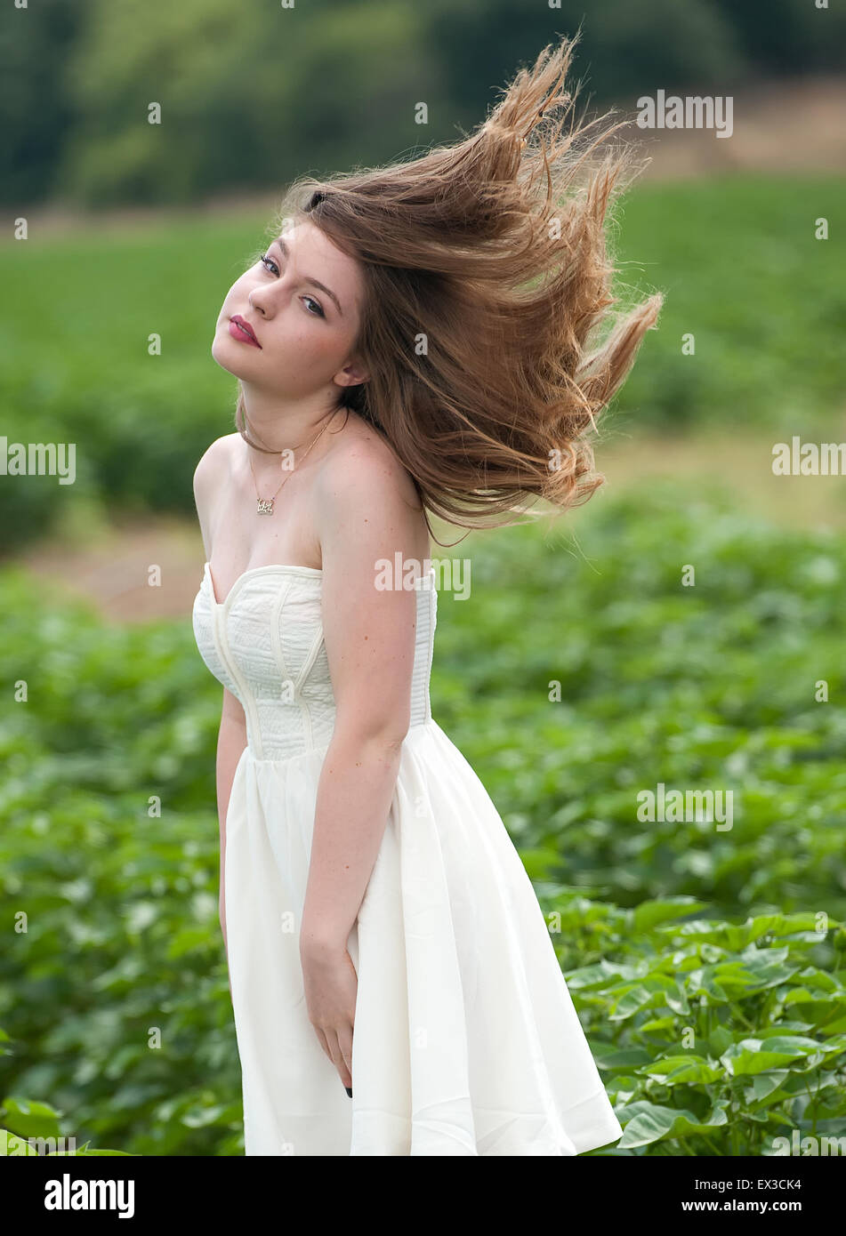 A young woman in a green field, hair blowing in the wind. Kibbutz Ha'solelim, Israel Stock Photo