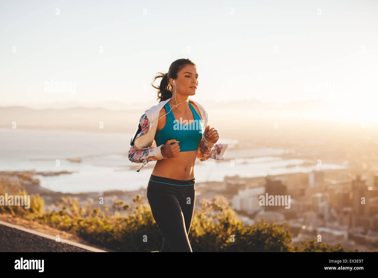Fit young woman jogging outdoors. Female athlete on morning run with bright light. Stock Photo