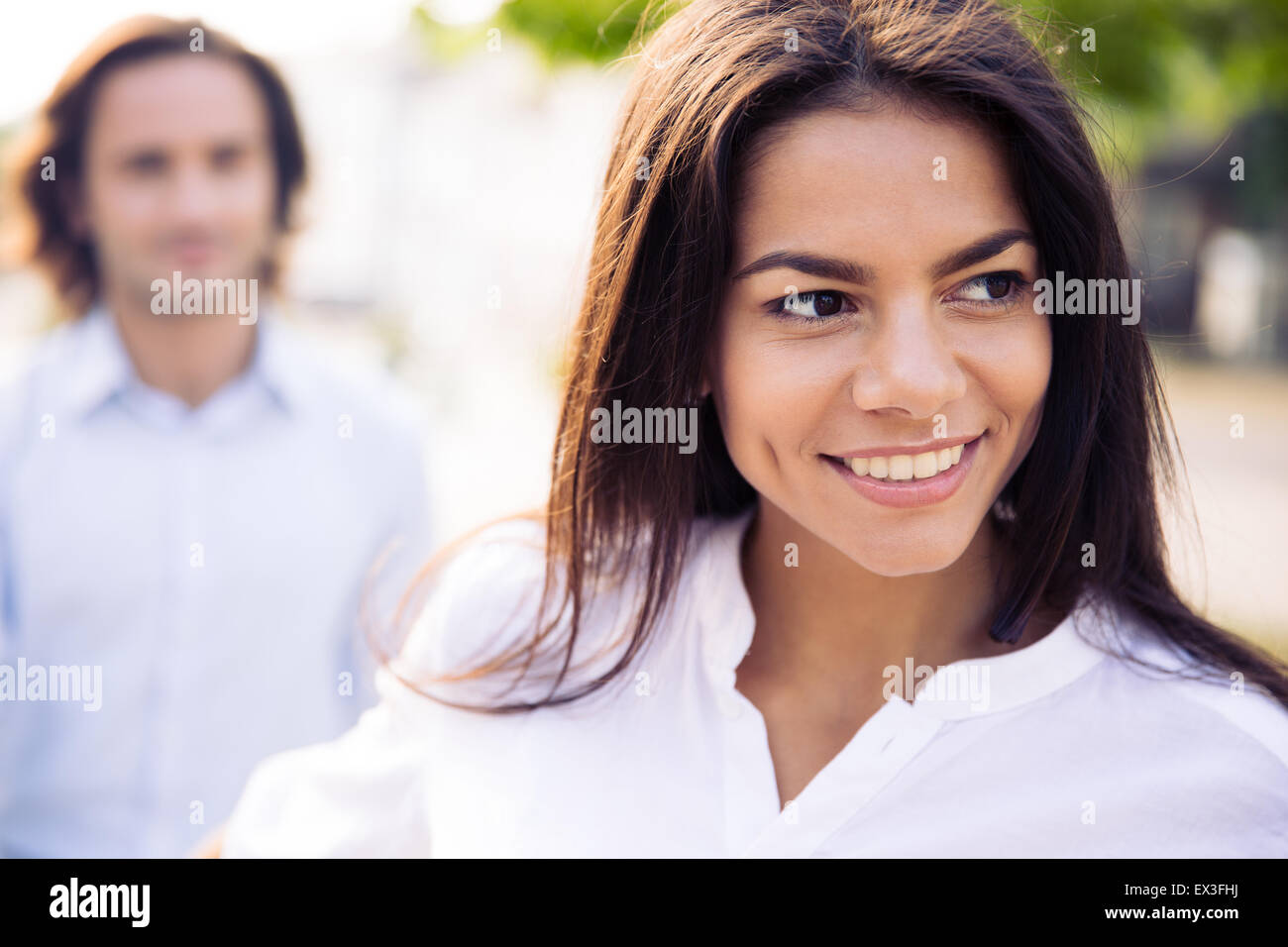 Smiling young woman holding man's hand and leading him outdoors Stock Photo