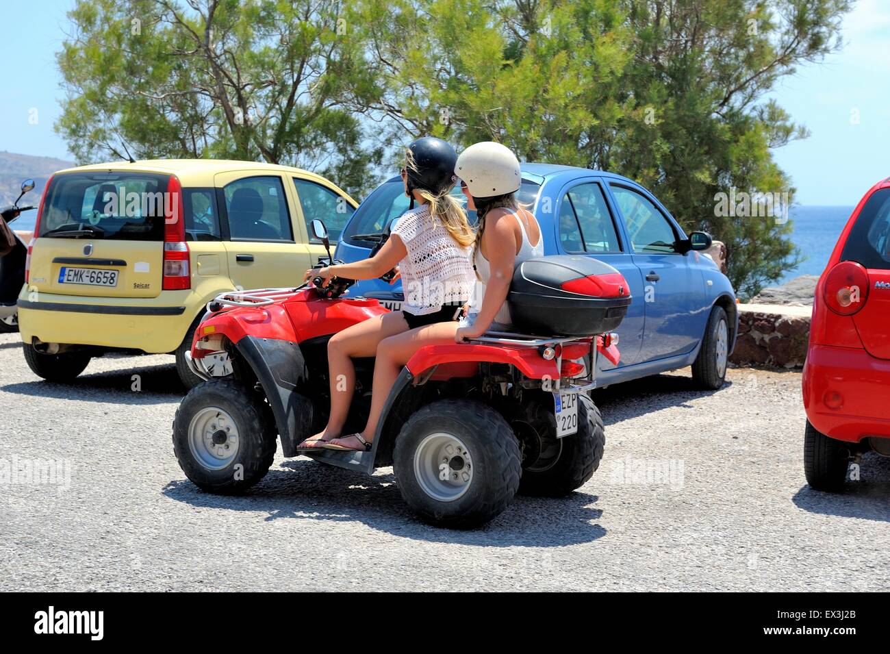 Two teenage girls riding an ATV quad rental bike in Akrotiri Santorini Greece Stock Photo