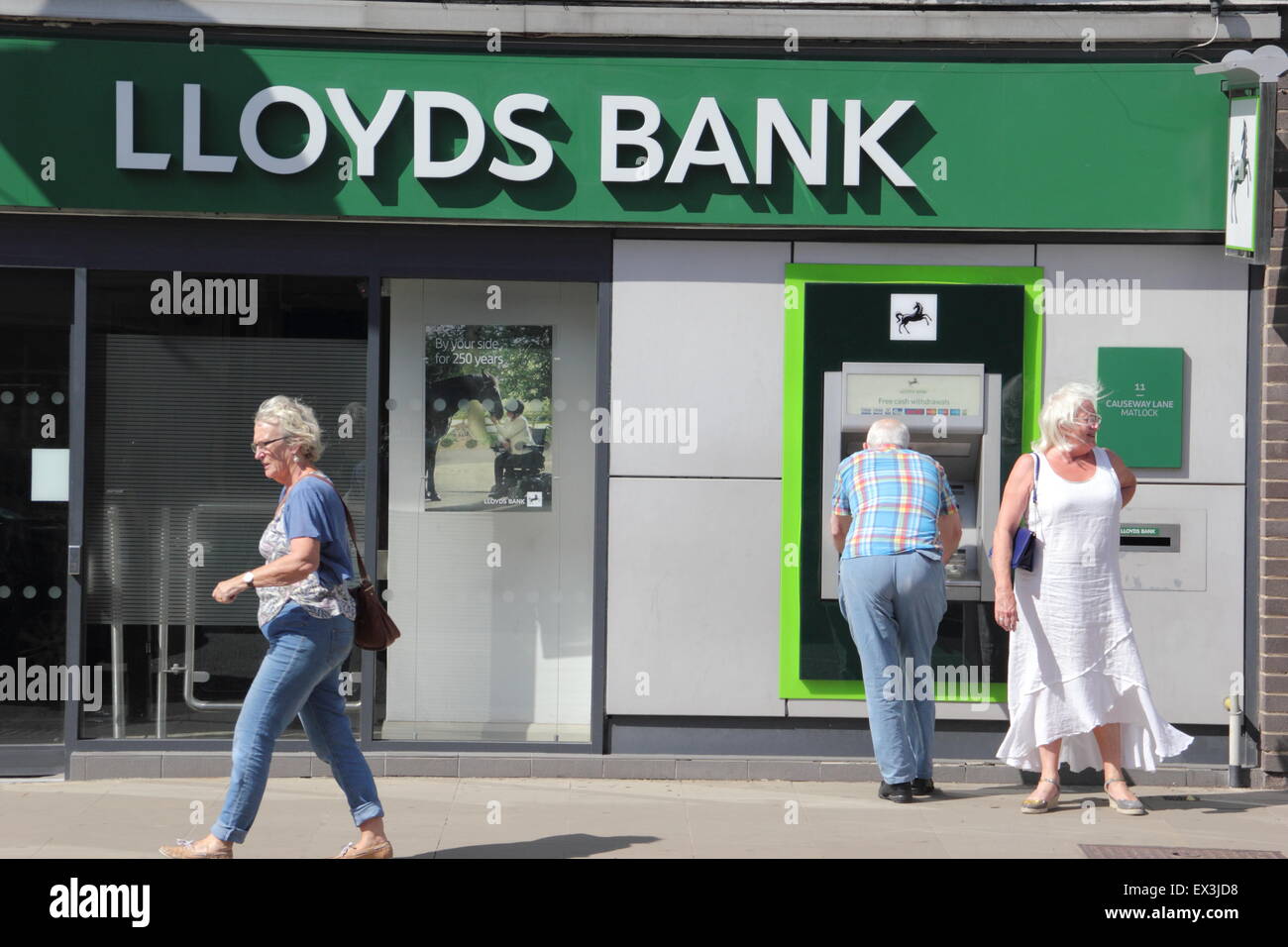 People use an ATM cashpoint machine at a Lloyds Bank branch in Derbyshire England UK Stock Photo