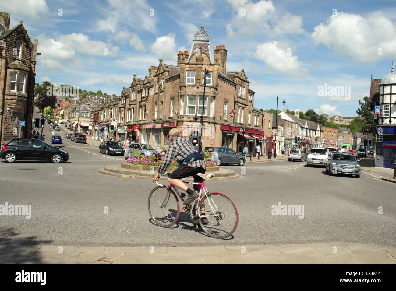 A cyclist navigates the roundabout  on Crown Square in Matlock town centre on a sunny summer's day, Derbyshire, England Stock Photo