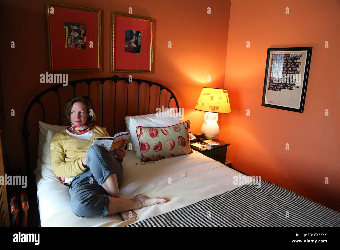 A woman sitting on a bed in Hotel Boheme in San Francisco's North Beach district of the city. Stock Photo