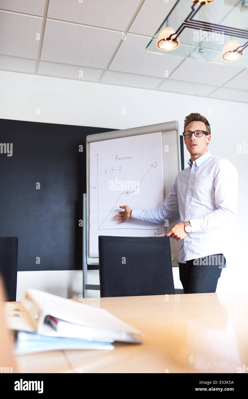 Young white male executive pointing to a chart on a whiteboard leading a meeting Stock Photo