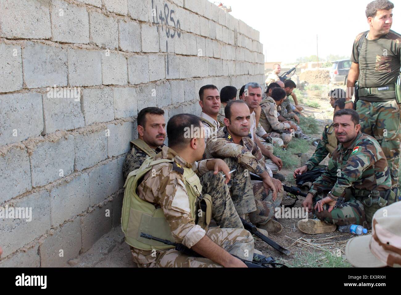 Kirkuk, Iraq. 6th July, 2015. Soldiers of Kurdish peshmerga forces sit near a wall in the front line to fight against Islamic State (IS) in the Murra village, some 30 km southwest of Kirkuk, north Iraq, July 6, 2015. Credit:  Xinhua/Alamy Live News Stock Photo