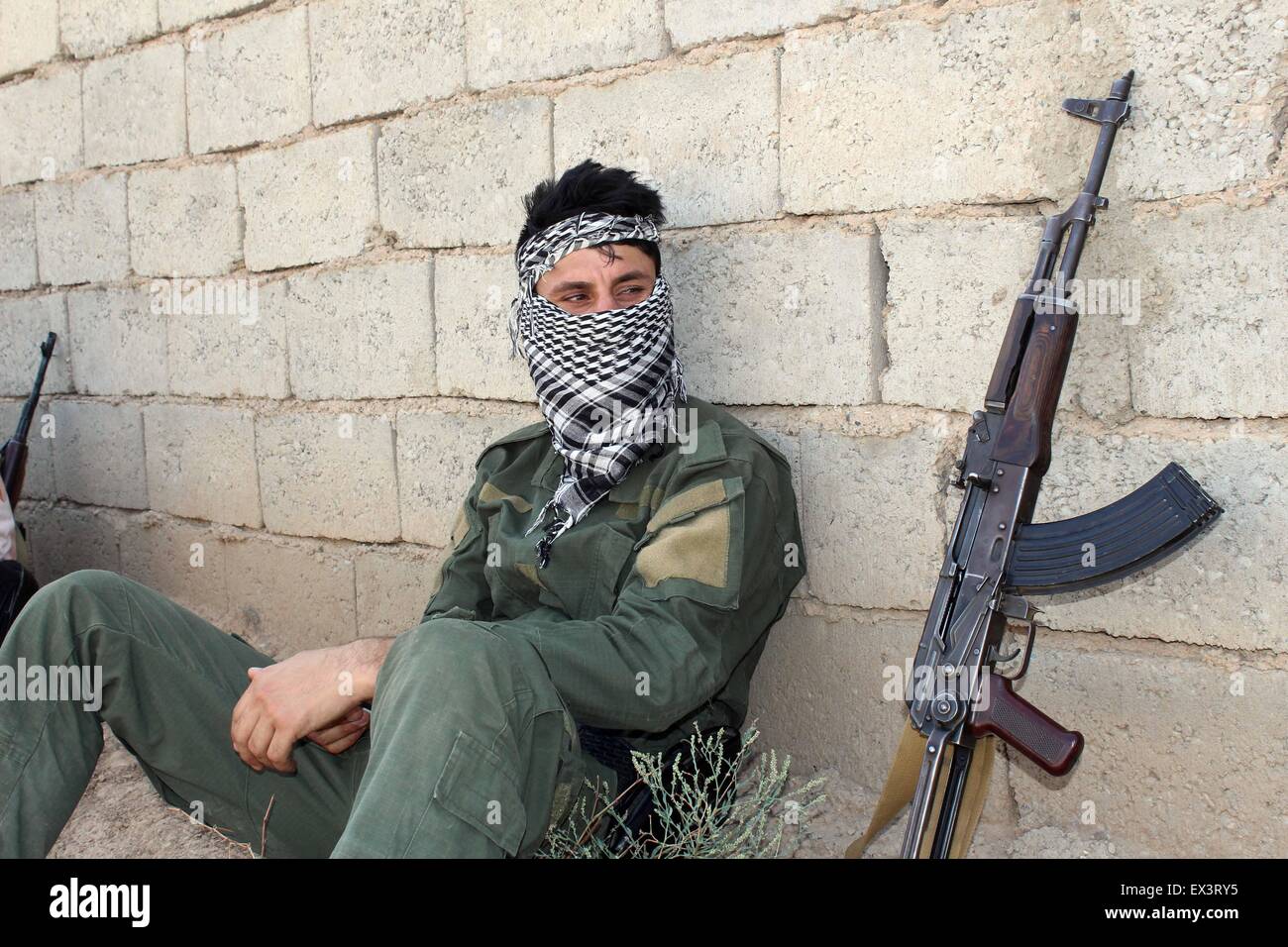 Kirkuk, Iraq. 6th July, 2015. A soldier of Kurdish peshmerga forces sits near a wall in the front line to fight against Islamic State (IS) in the Murra village, some 30 km southwest of Kirkuk, north Iraq, July 6, 2015. Credit:  Xinhua/Alamy Live News Stock Photo