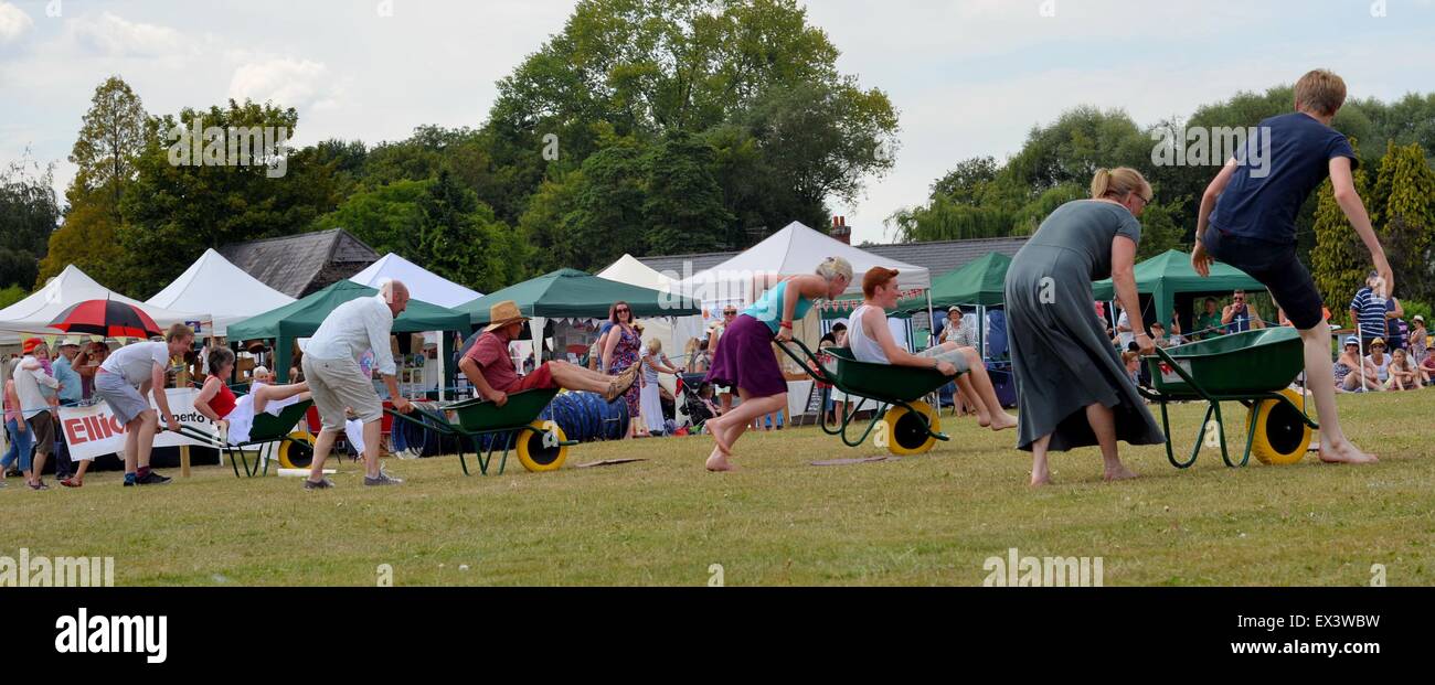 Adults competing in a wheelbarrow race at a country fair in Hampshire, UK Stock Photo