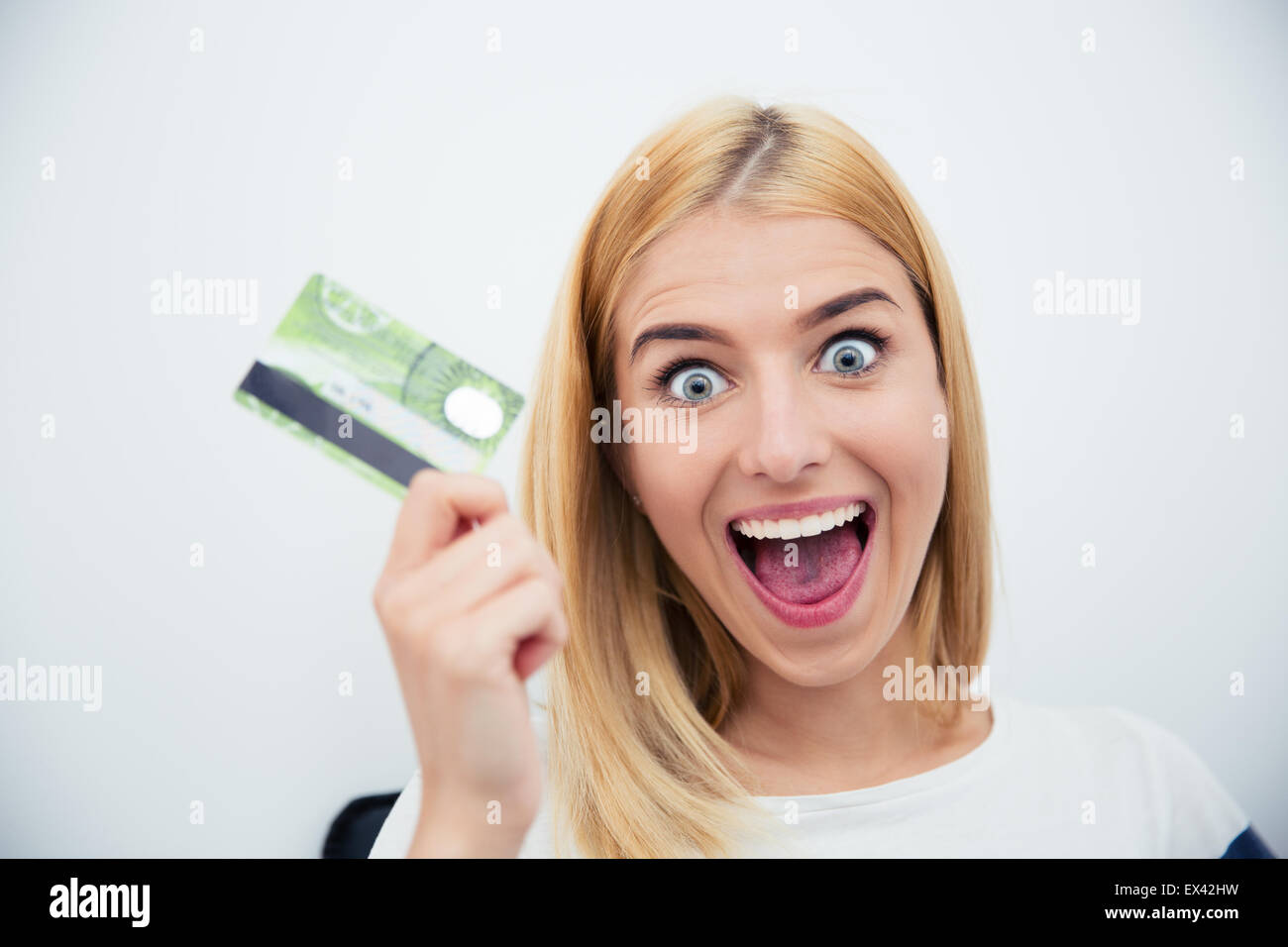 Cheerful young woman holding bank card over gray background Stock Photo