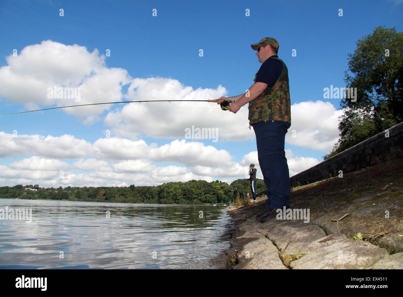 Fly fishing from reservoir dam with blue sky and clouds Stock Photo