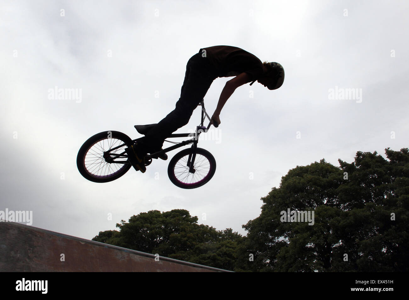 BMX cyclist silhouetted against grey sky Stock Photo