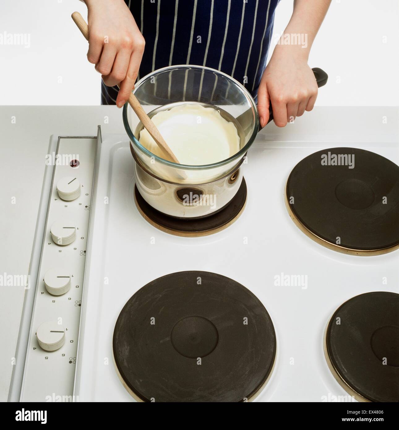Melting white chocolate in glass bowl on top of saucepan on electric