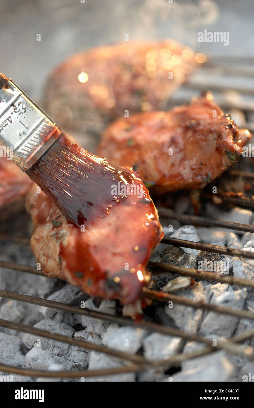 Meat on barbecue grill being glazed with paint brush Stock Photo Alamy