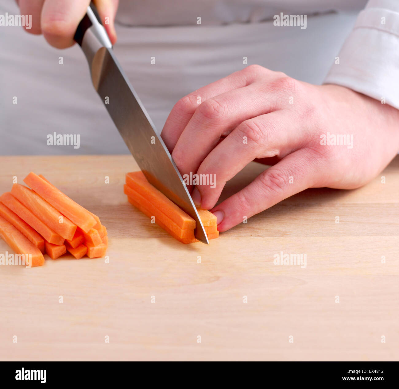 Cutting carrots into strips with large knife, close-up Stock Photo