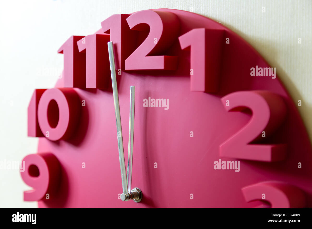 Red clock showing five to midnight on the face Stock Photo