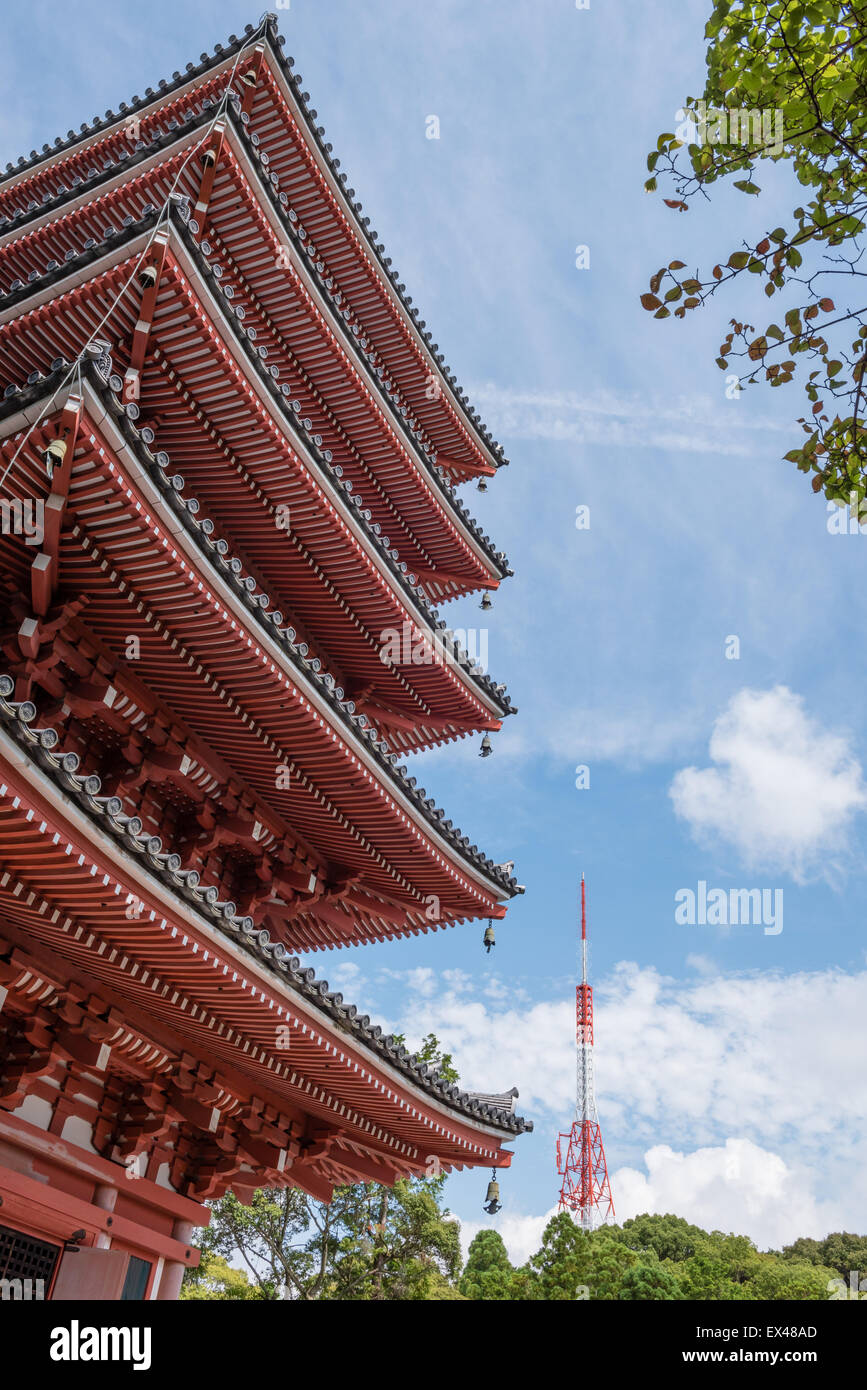 A 5 story Japanese pagoda positioned next to a modern red and white radio tower and a blue sky with clouds in the background. Stock Photo