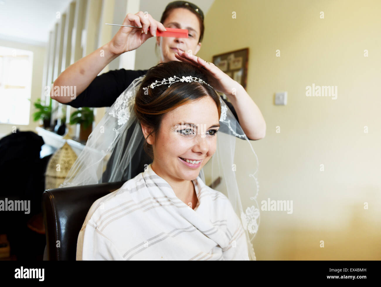 Young bride having her wedding hair done by hairdresser who is