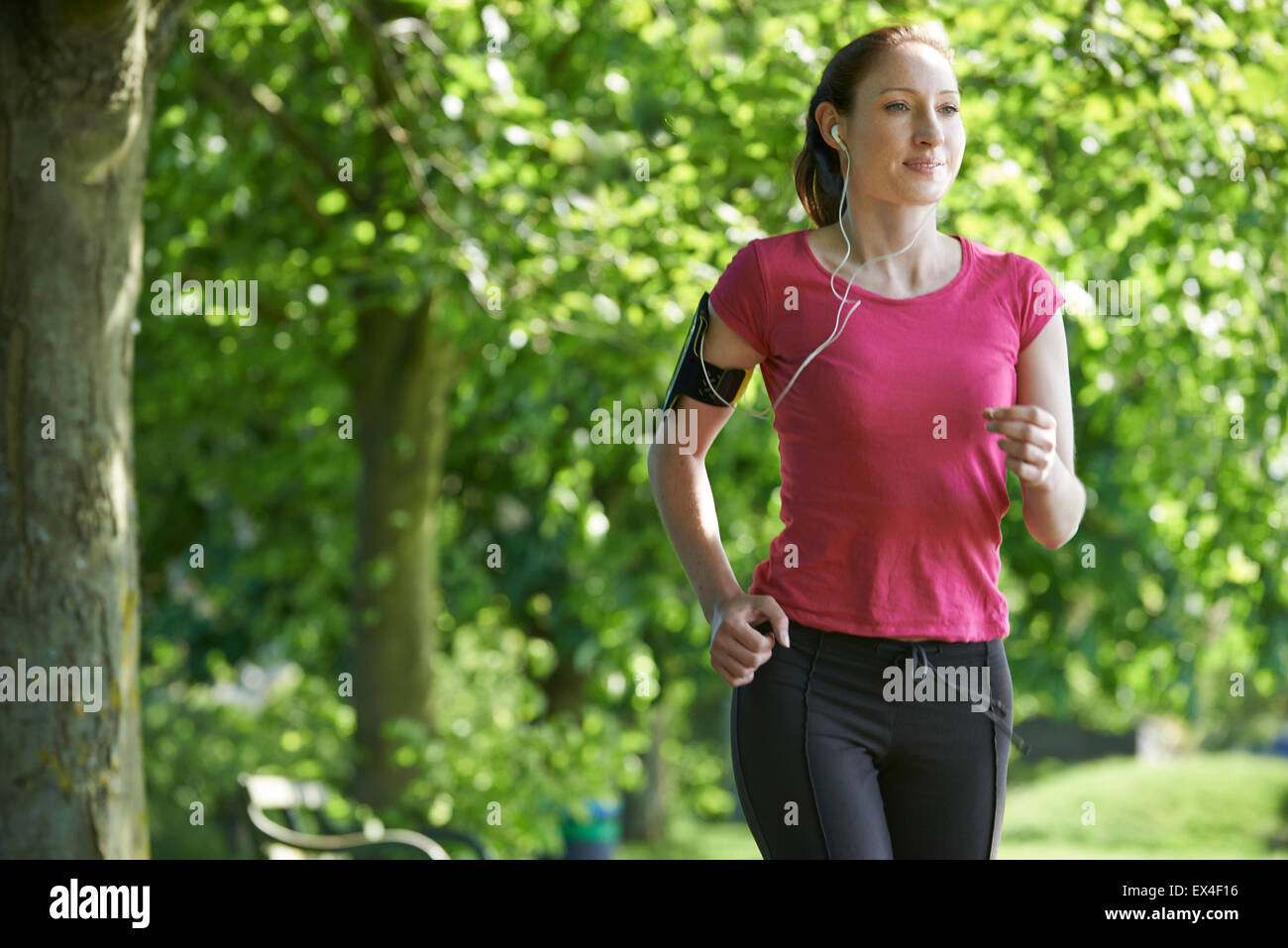 Female Runner In Park With Wearable Technology Stock Photo