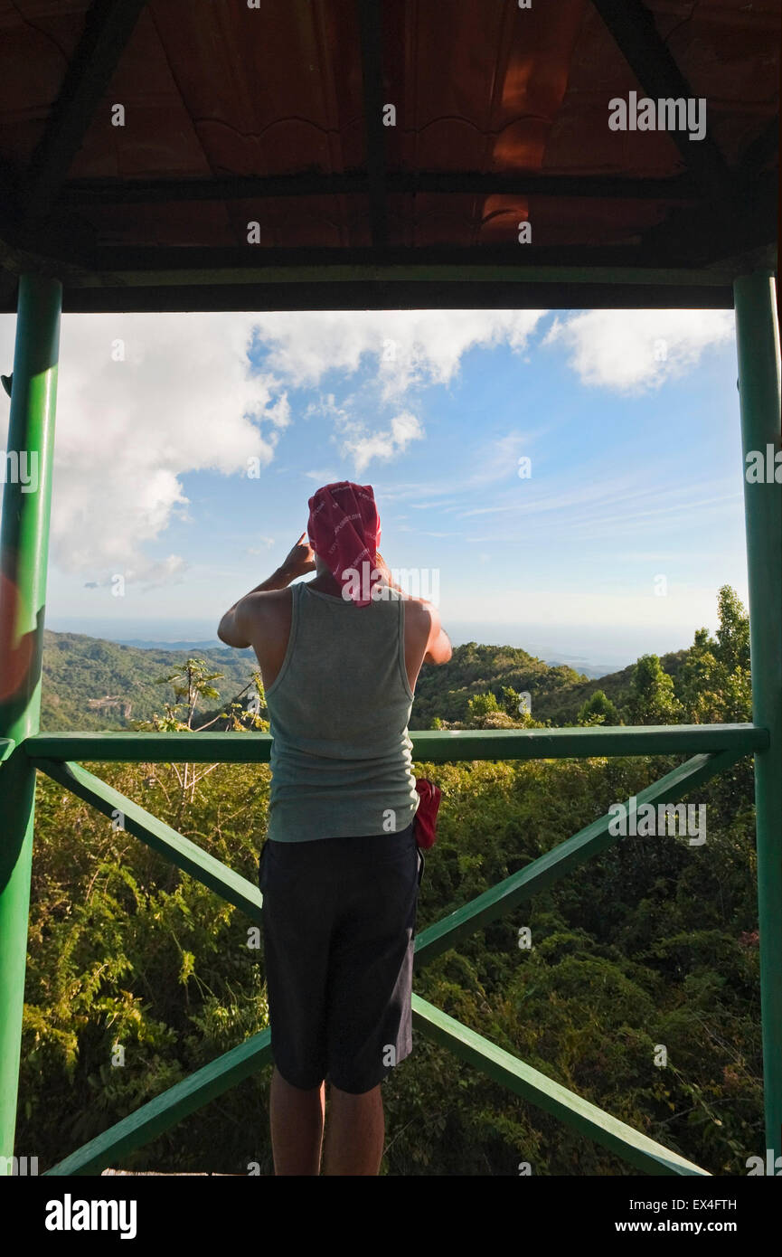 Vertical view of a tourist taking photos from a lookout post in Topes de Collantes National Park in Cuba. Stock Photo