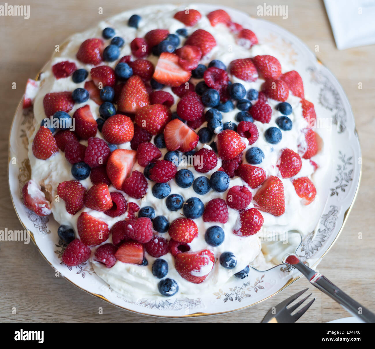 Pavlova cake with strawberry, blueberry, raspberry and whipped cream