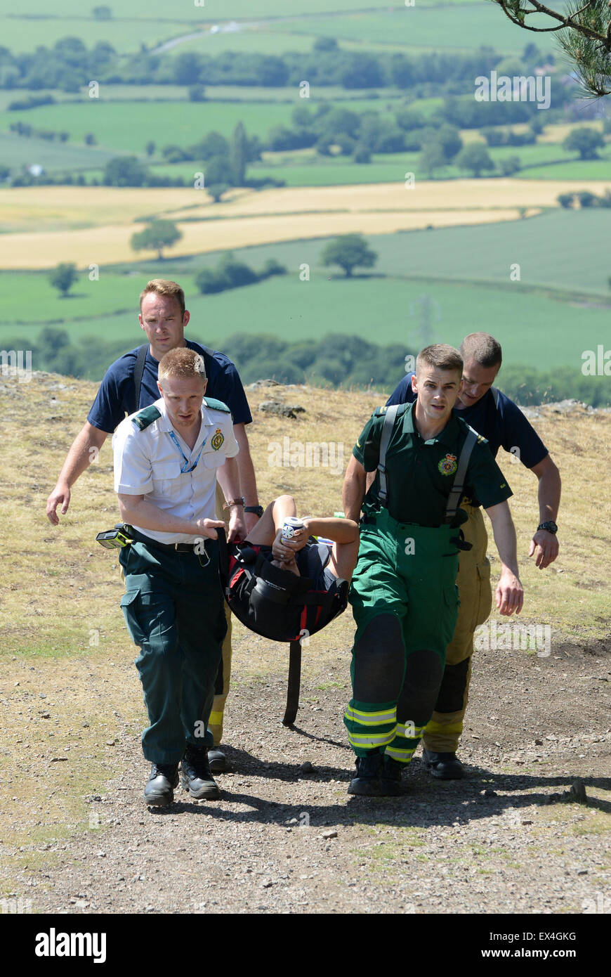 Shropshire Ambulance Service and Shropshire Fire and Rescue officers carry injured woman back to ambulance Wrekin Hill Uk Stock Photo