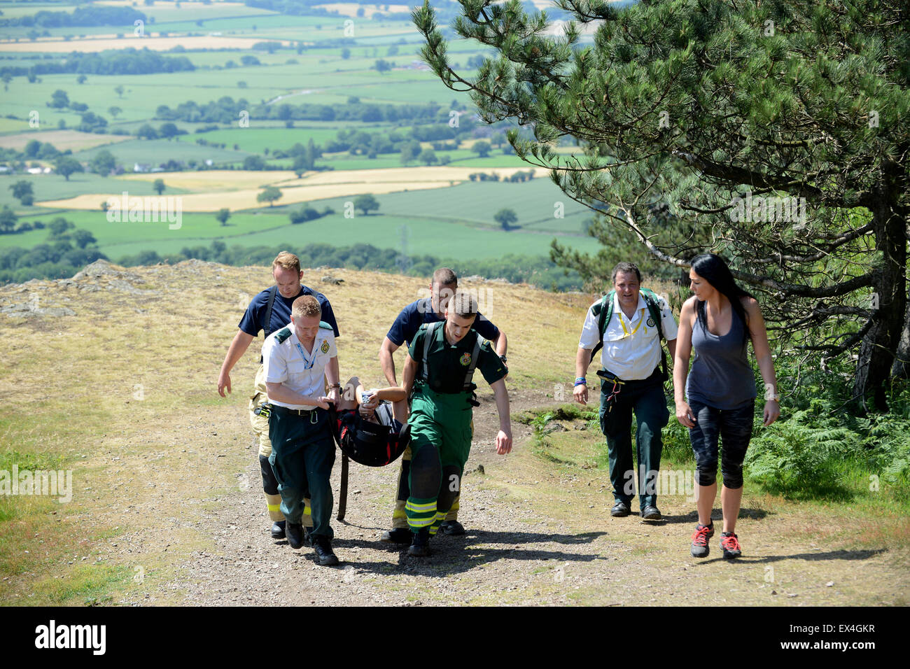 Shropshire Ambulance Service and Shropshire Fire and Rescue officers carry injured woman back to ambulance Wrekin Hill Uk Stock Photo