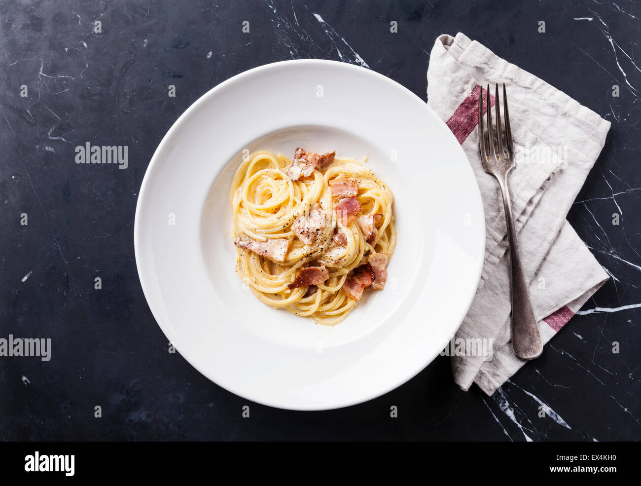 Pasta Carbonara on white plate with parmesan on dark marble background Stock Photo