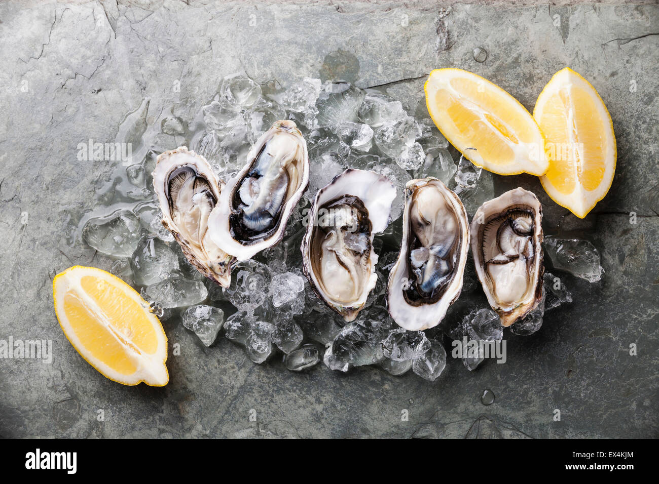 Opened Oysters on stone plate with ice and lemon Stock Photo