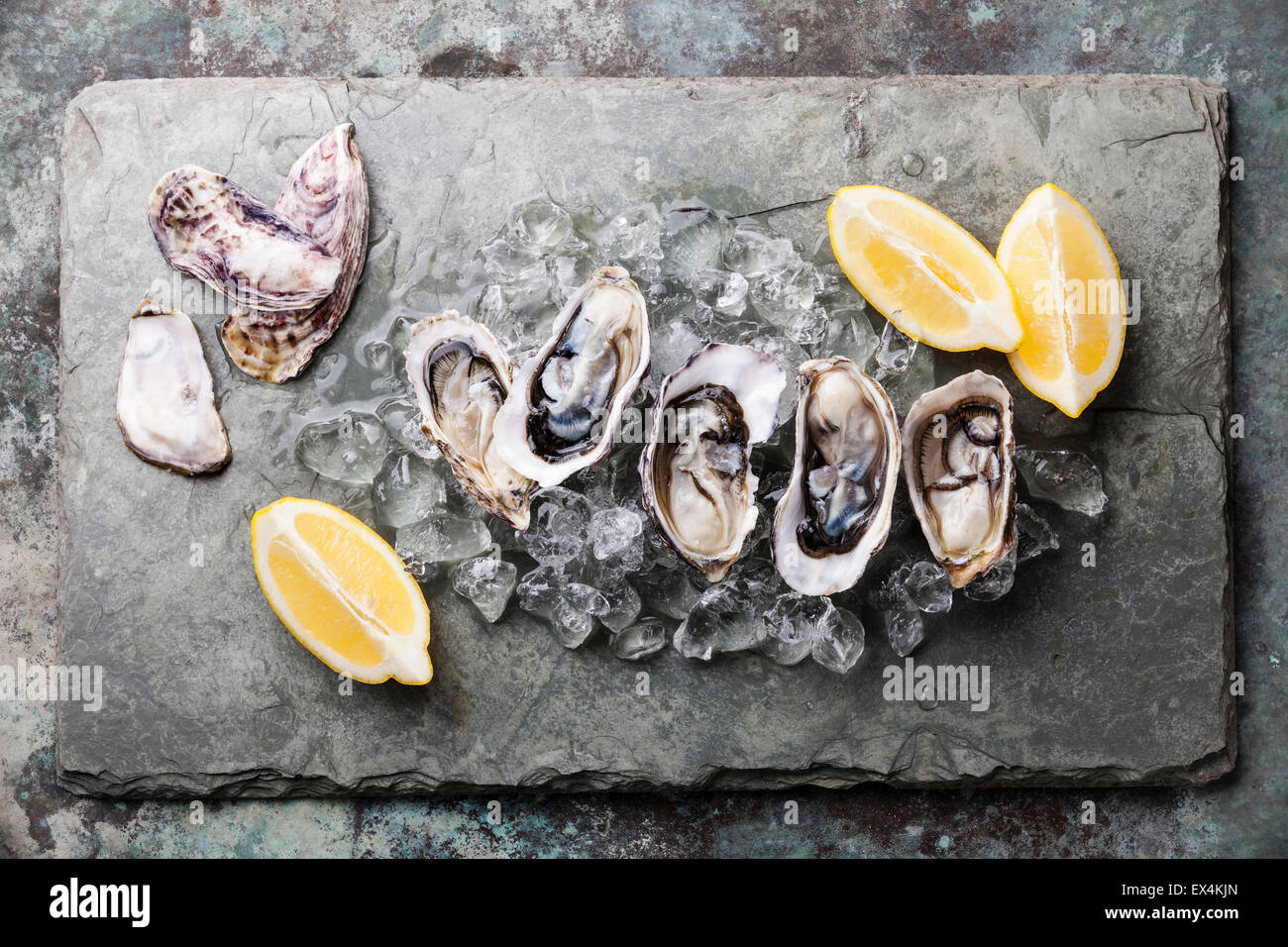 Opened Oysters on stone plate with ice and lemon Stock Photo
