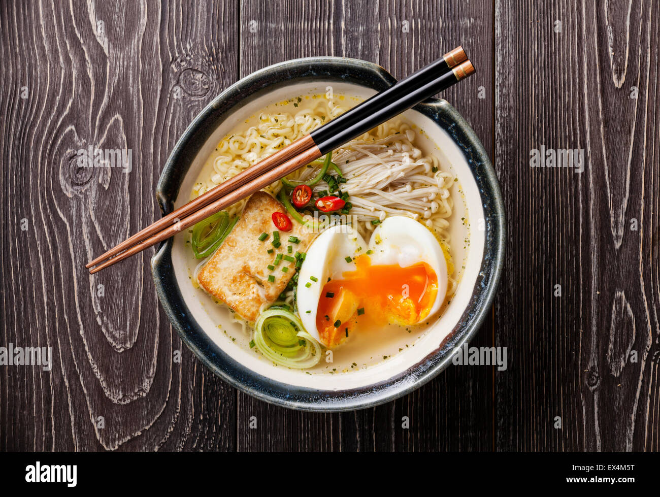 Asian Miso ramen noodles with egg, tofu and enoki in bowl on gray wooden background Stock Photo