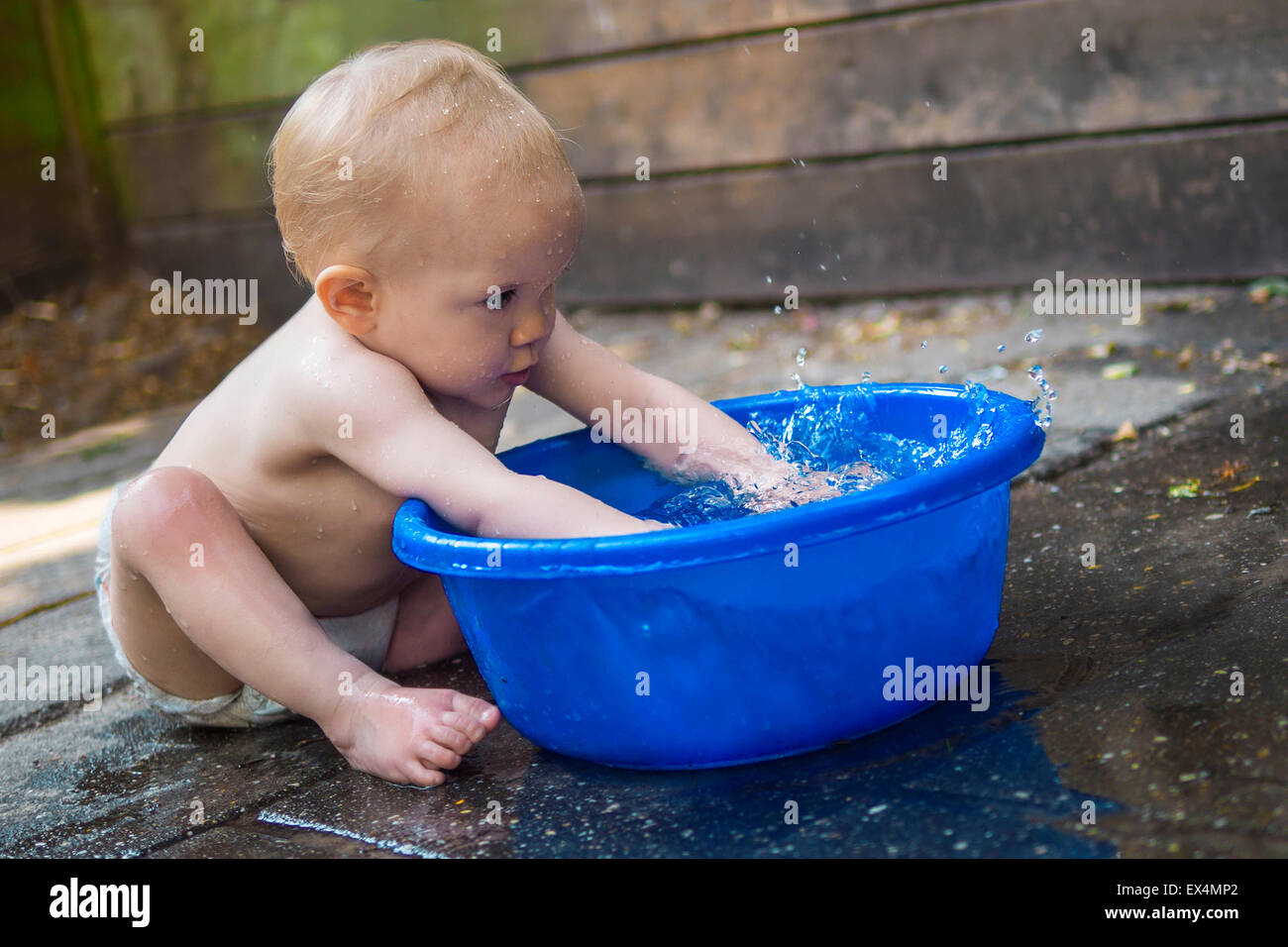 Cute baby playing with a tub of water Stock Photo