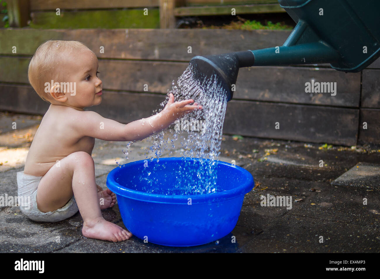 Beautiful baby playing with water outdoors Stock Photo