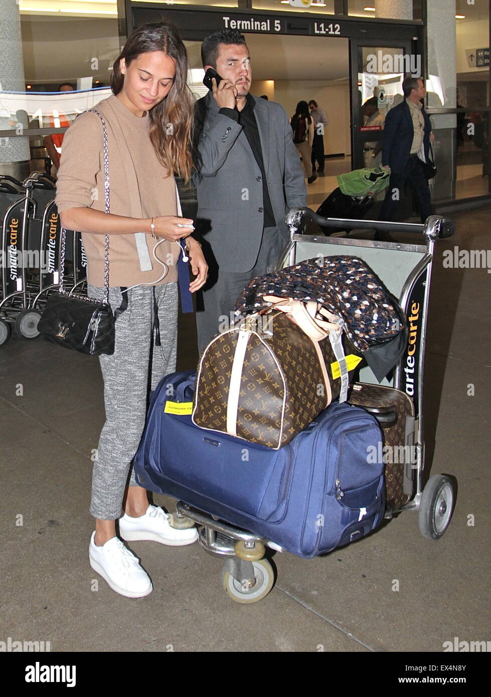Alicia Vikander cradles a baby while at an airport with husband